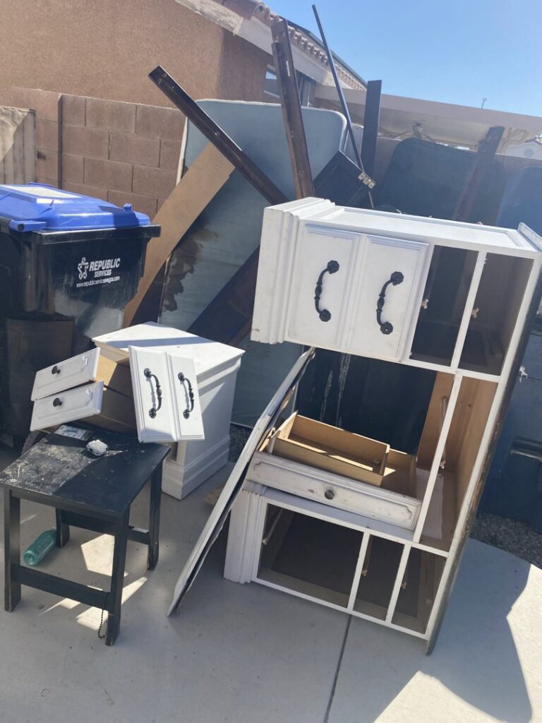 Broken furniture pieces and a trash can outside a home, ready for junk removal by Road Dogz Hauling in Las Vegas, NV.