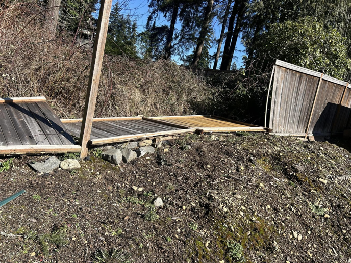 Broken wooden fence panels lying on the ground, indicating damage requiring handyman service from HandyMan Shocks in Tacoma, WA.