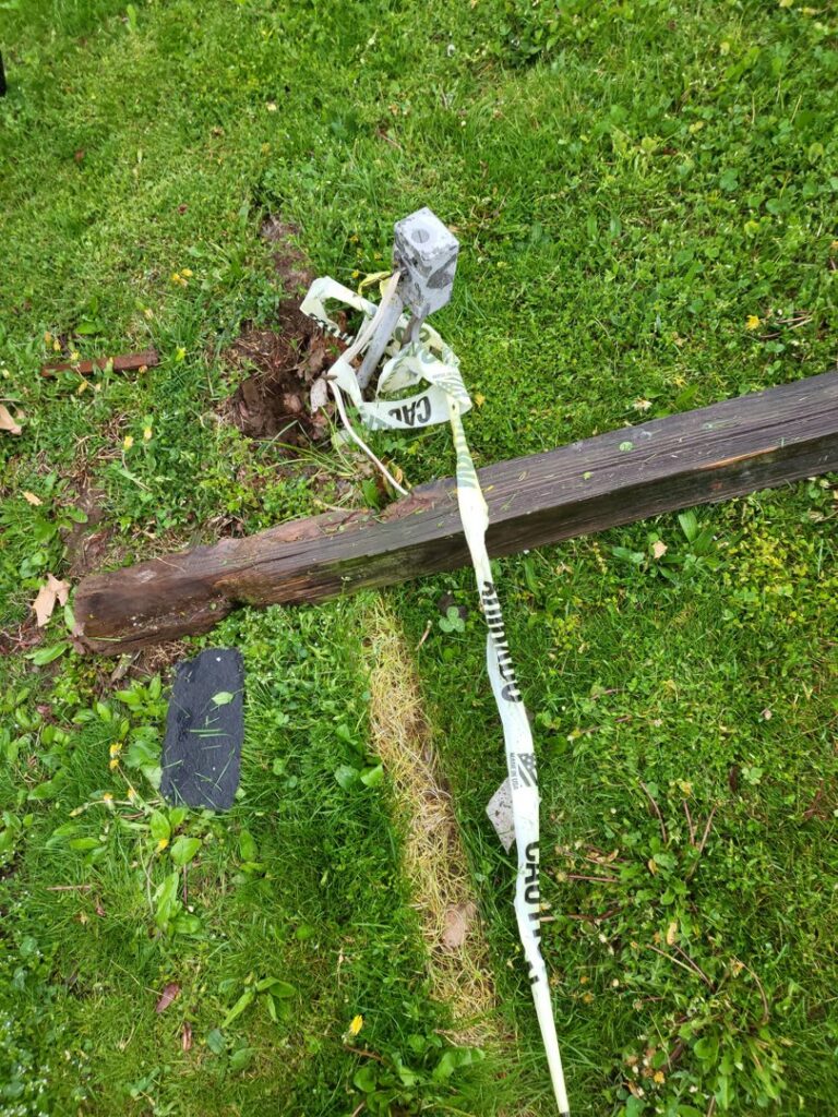 A broken wooden post in the grass, ready for repair by Green Man's Contracting & Landscaping LLC in West Hartford, CT.