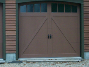 A brown garage door with an X-pattern design and arched windows, installed by Harold Carpenter Overhead Door inc in Oshkosh, WI.