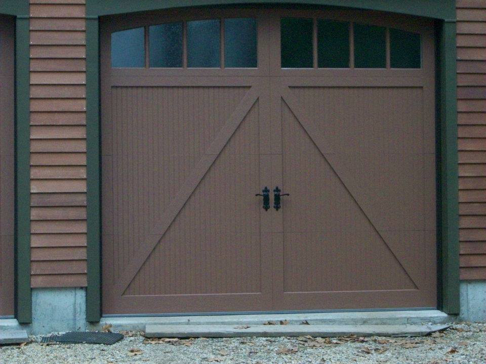 A brown garage door with an X-pattern design and arched windows, installed by Harold Carpenter Overhead Door inc in Oshkosh, WI.