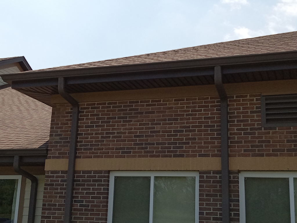 Brown gutters and shingle roof on a brick building, showing exterior services by Coburns interior and exterior in Services Available In.