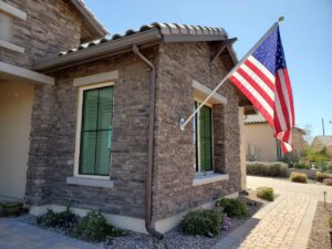 A house featuring a brown rain gutter, downspout, and sun screens on windows, installed by Phoenix Rain Gutters and Sun Protection in Glendale, AZ.