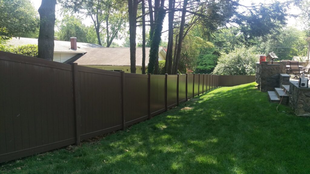 A long brown vinyl privacy fence installed in a backyard by Quality Fence & Deck Co. in Frederick, MD.