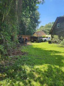 Workers clearing brush and loading tree debris into a trailer, showcasing land clearing services by Ayla Tree Service in Bloomingdale, GA.