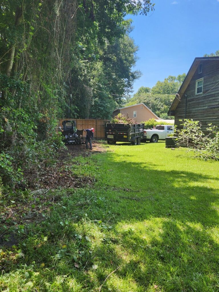 Workers clearing brush and loading tree debris into a trailer, showcasing land clearing services by Ayla Tree Service in Bloomingdale, GA.