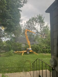 Capital Tree Company worker in a bucket lift performing tree trimming services in a residential area of Des Moines, IA.