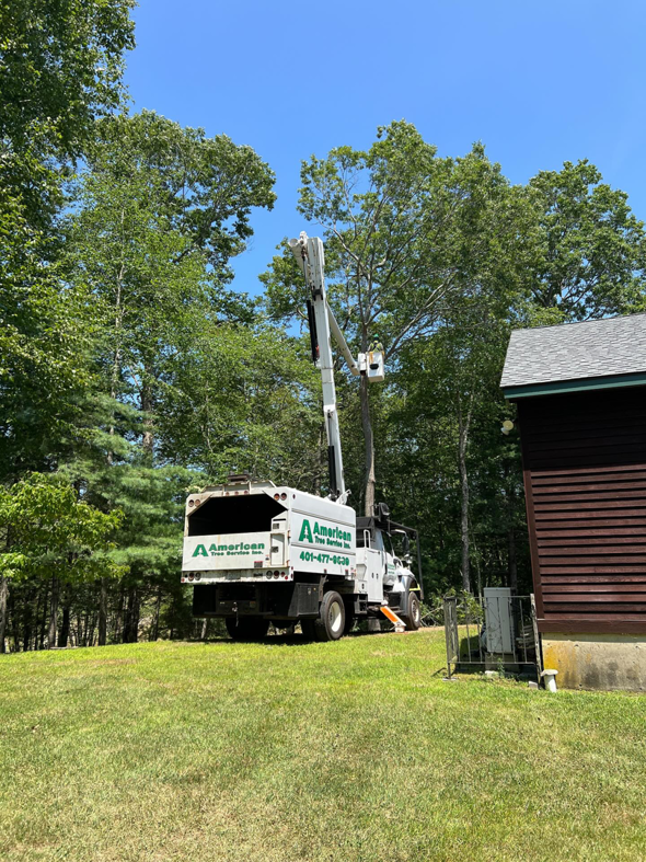 A bucket truck from American Tree Service, Inc. extended for tree trimming in Coventry, RI.