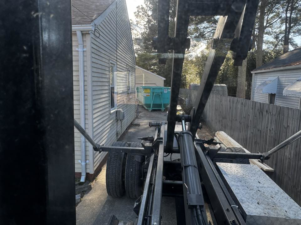 A Budget Boxx dumpster being delivered or picked up at a residential property for junk removal in Suffolk, VA.