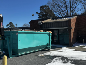A Budget Boxx dumpster full of construction debris outside a building, ready for junk removal in Suffolk, VA.
