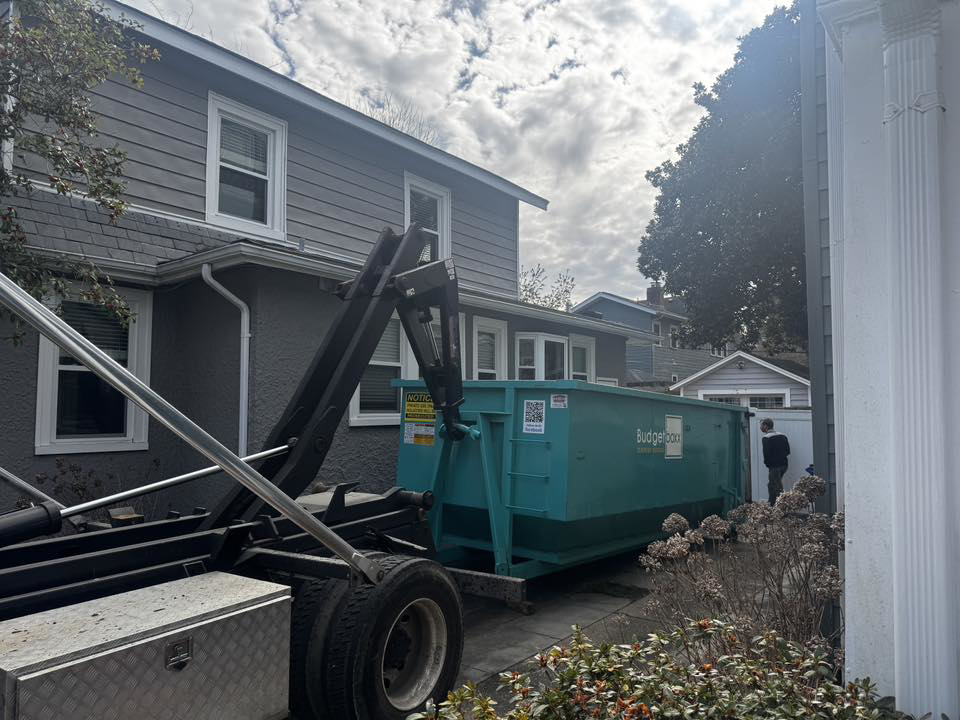 A Budget Boxx truck deploying a dumpster for junk removal service at a residential home in Suffolk, VA.
