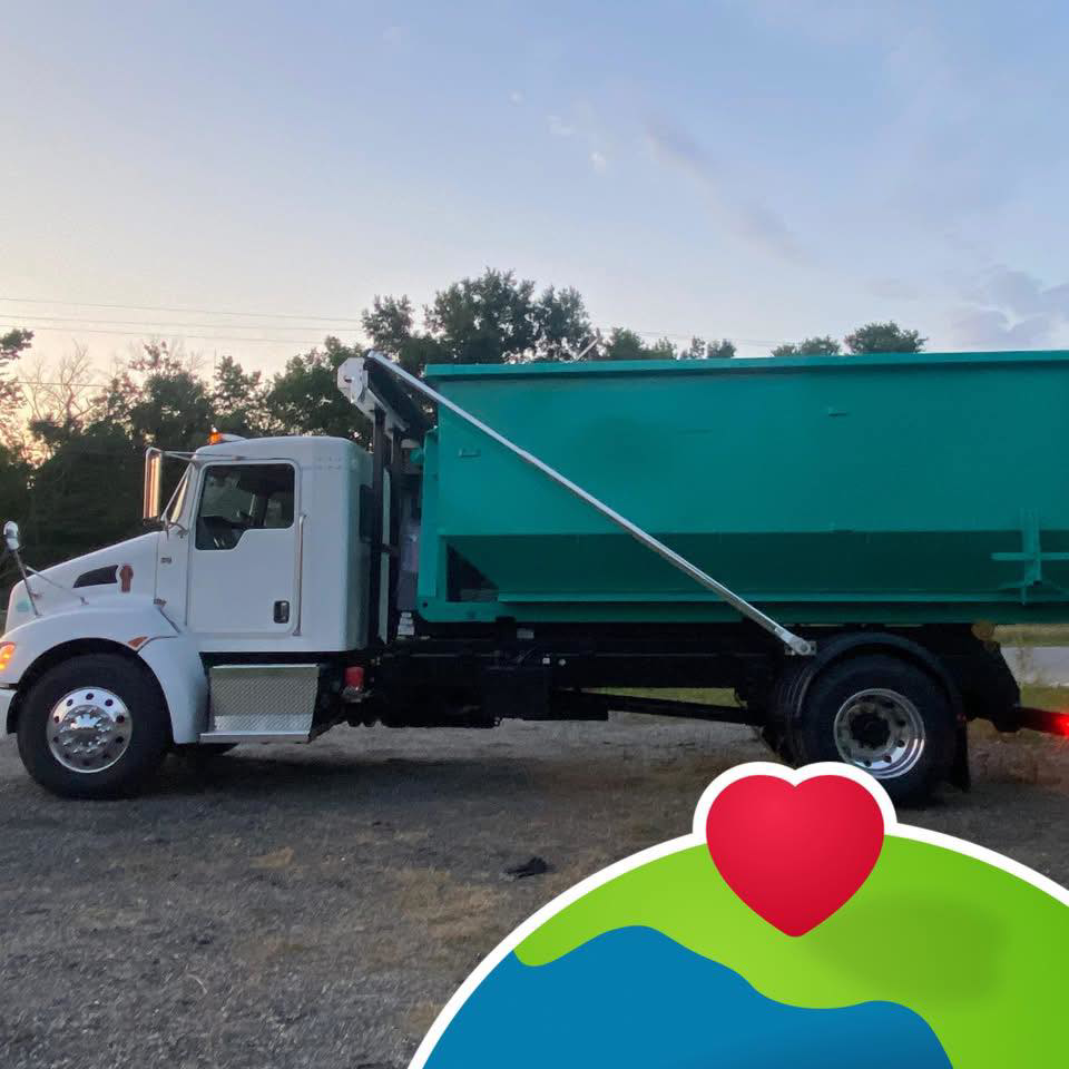 A Budget Boxx junk removal truck with a green dumpster attached, ready for service in Suffolk, VA.