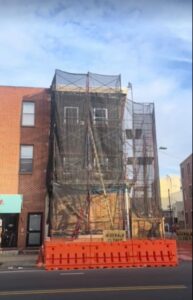 A building under construction with scaffolding and protective netting by MCG General Contractor in Philadelphia, PA.