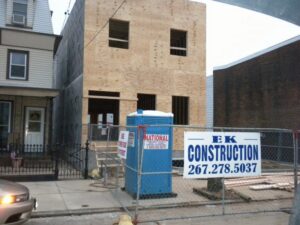 A building under construction with plywood sheathing and an EK Construction sign in Philadelphia, PA