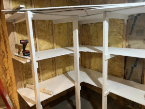 Handyman building custom white shelves with a drill, showing work in progress by Halls Home Solutions in Pierre, SD