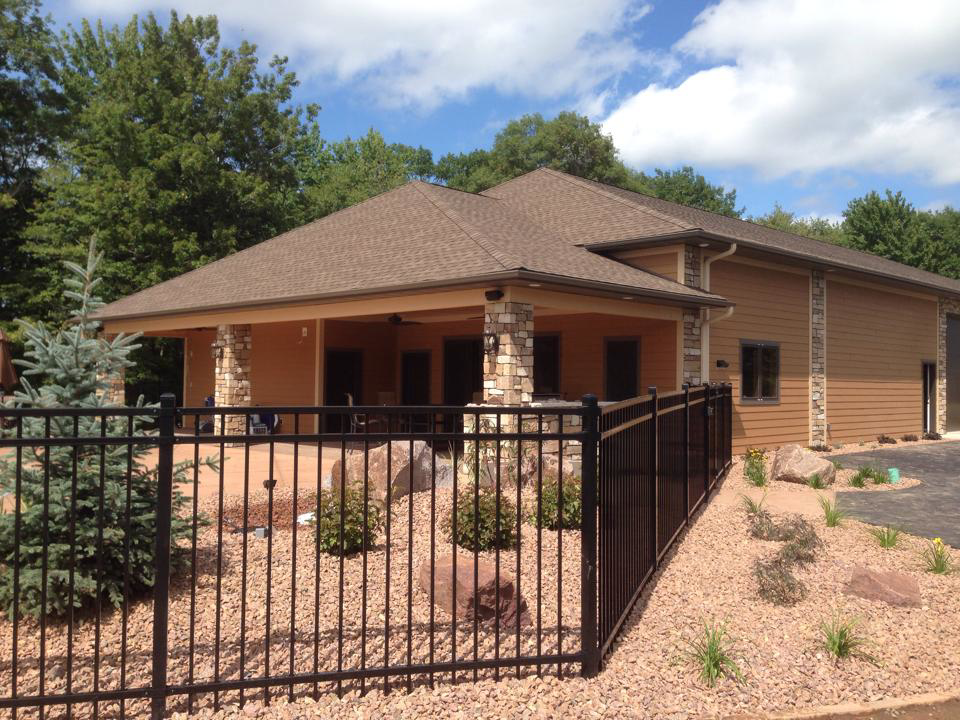 The exterior of a modern building with a black metal fence and professional landscaping by Ankeny Builders L.L.C. in Eau Claire, WI.