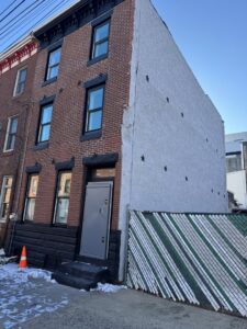 Exterior view of a renovated building with new stucco siding and brickwork by MCG General Contractor in Philadelphia, PA.
