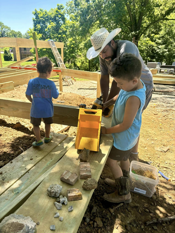 A man and children actively building a wooden deck frame, showcasing construction services by DELM Construction & Remodeling LLC in Evansville, IN.