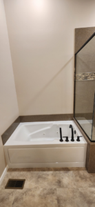 A newly installed built-in bathtub with modern black fixtures by Willhite Construction in O'Fallon, MO.
