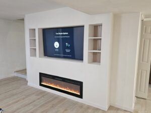A custom built-in media center with a television and electric fireplace, designed and built by Modern Remodel Build & Design in Worcester, MA.