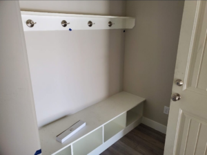 A white built-in mudroom bench with cubbies and coat hooks installed by Blue Ridge Customs LLC in Raleigh, NC.