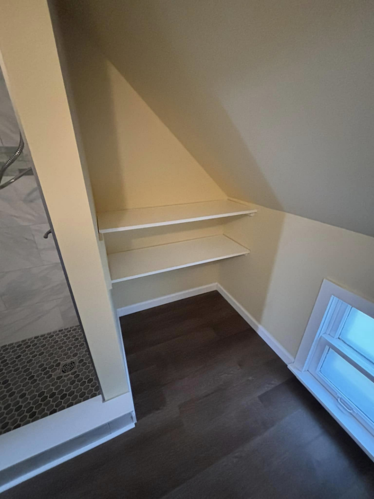 Newly installed built-in shelves in a renovated bathroom corner by T-N-T Mechanical in Westland, MI.
