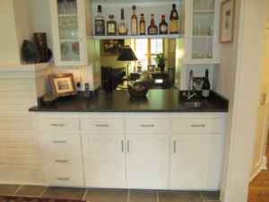 A newly installed built-in wet bar with white cabinets, dark countertop, and sink by Jackson Construction in Oak Hills Place, LA