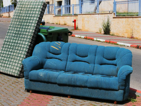 An old blue sofa and a mattress left on a sidewalk, awaiting bulky item removal by Trashouts Junk Removal in Pembroke Pines, FL.