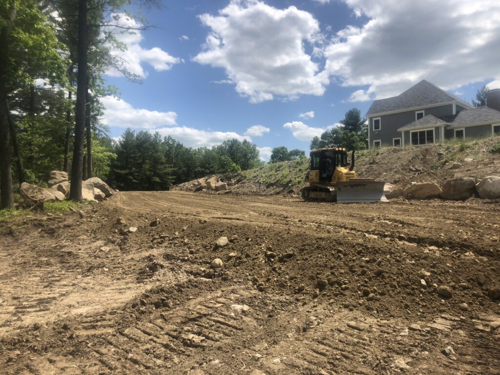 A bulldozer performing land grading and site preparation for a residential property by Solimini Excavation and Utility in Freetown, MA
