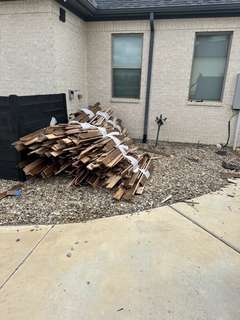 Bundled wood debris and construction waste piled next to a house for removal by JB'S Junk Removal in Justin, TX.