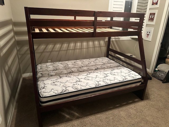 A newly assembled wooden bunk bed with a mattress on the bottom by Henderson Handyman in Henderson, NV