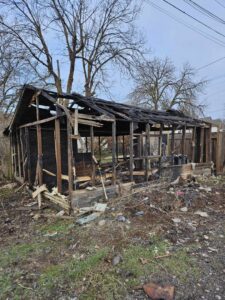 A burnt and partially demolished shed, with debris ready for removal by Primetime Hauling and Junk Removal in Spokane, WA.