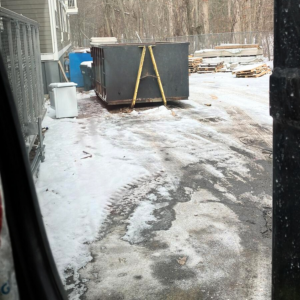 A BusyBee Disposal dumpster at a snowy construction or industrial site in Everett, MA, ready for debris removal.