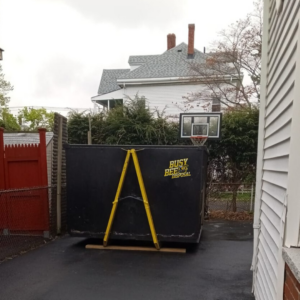 A BusyBee Disposal dumpster placed in a residential driveway or backyard in Everett, MA, for junk removal services.