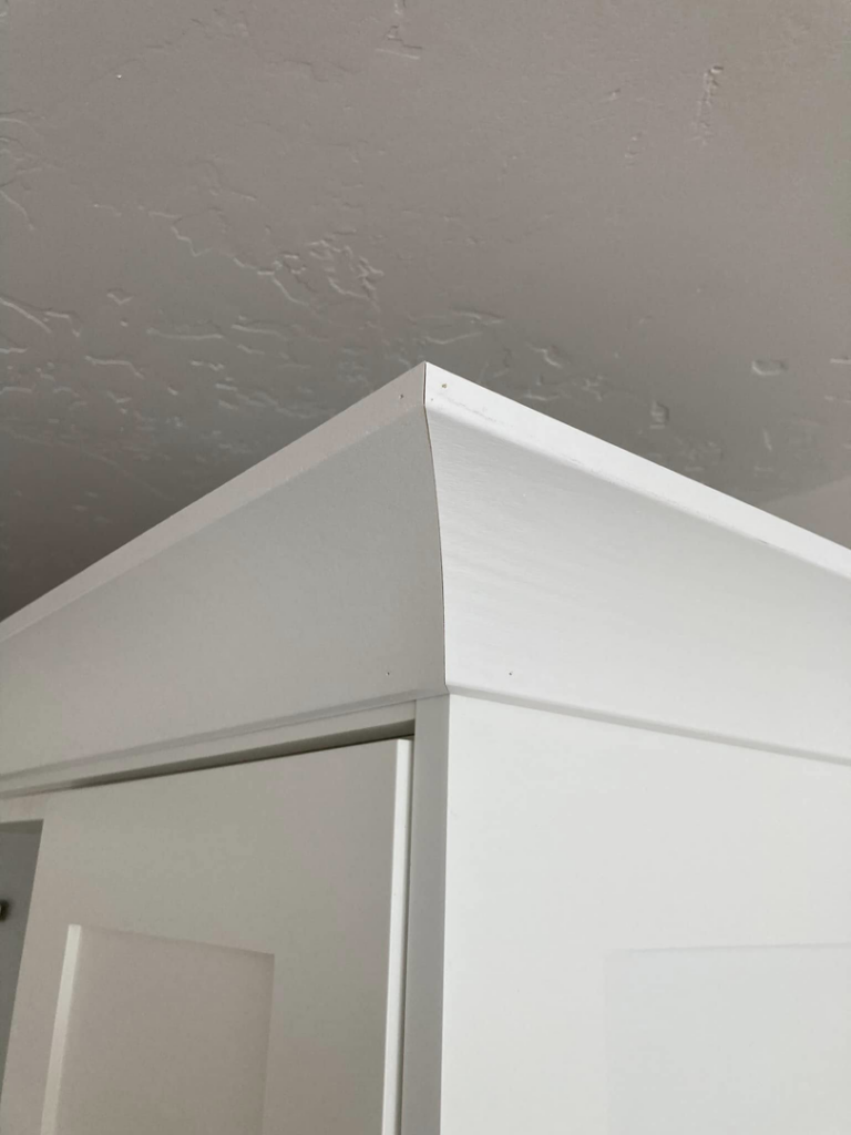 Close-up of newly installed white crown molding on top of kitchen cabinets, a handyman service by JMY Construction in Meridian, ID.