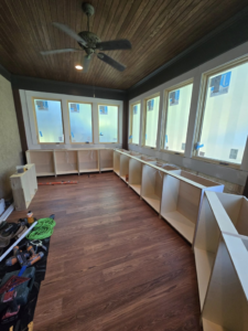 Handyman installing new base cabinets in a room, with tools on the floor, by Sanchez Construction Services in Laredo, TX.