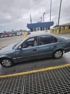 A blue car being weighed on a scale at the SA Recycling - Long Beach Ave facility in Los Angeles, CA.