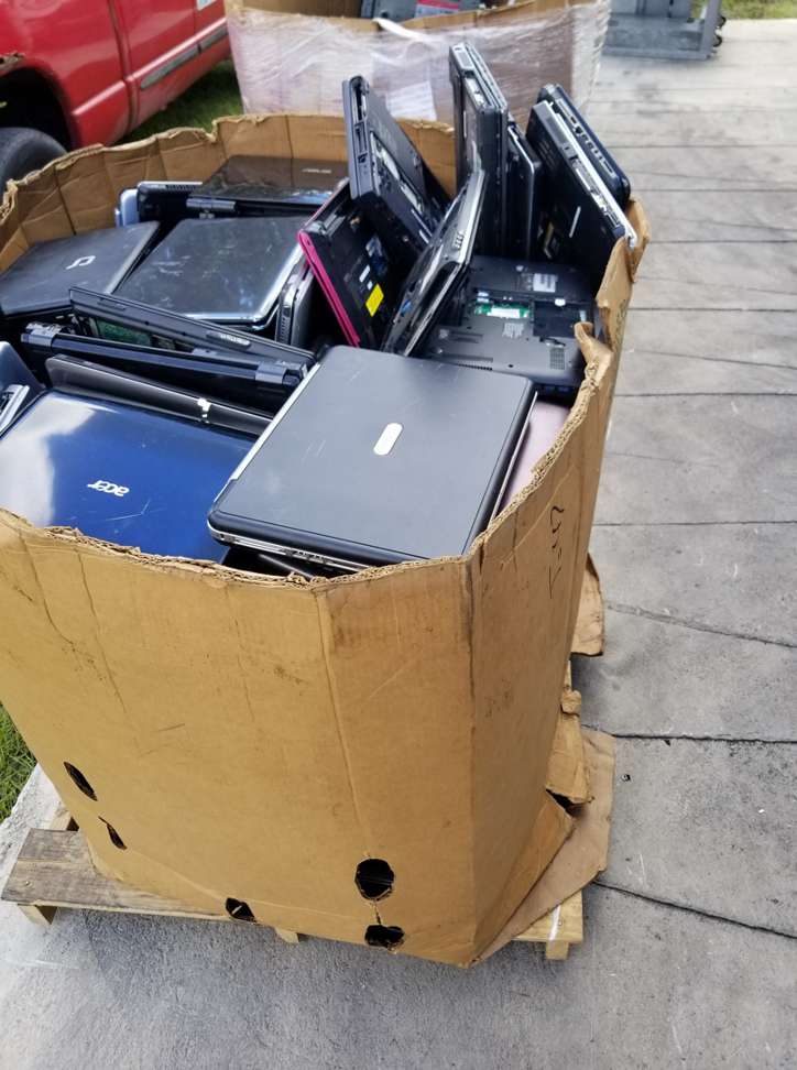 A large cardboard box overflowing with old laptops and electronic devices ready for recycling by Treasure Coast Electronic Recycling in Port St. Lucie, FL.