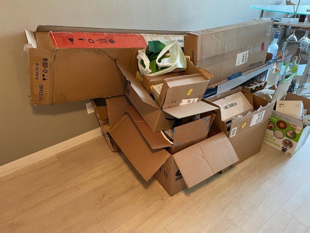 A stack of cardboard boxes and other items inside a room for junk removal by Elite Hauling & Junk Removal in San Diego, CA.