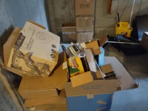 A pile of cardboard boxes and miscellaneous junk in a basement, ready for removal by 1-800-Declutter in Cincinnati, OH.