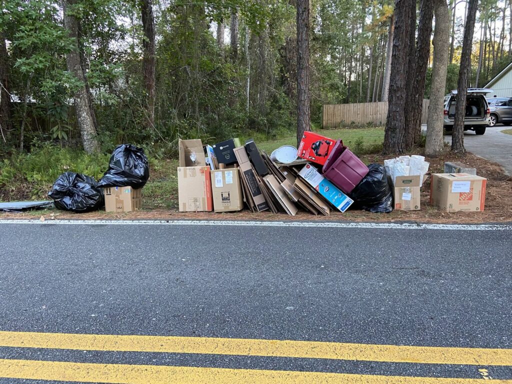 Piles of cardboard boxes and trash bags placed curbside for pickup by Junk Removal JAX in Jacksonville, FL.