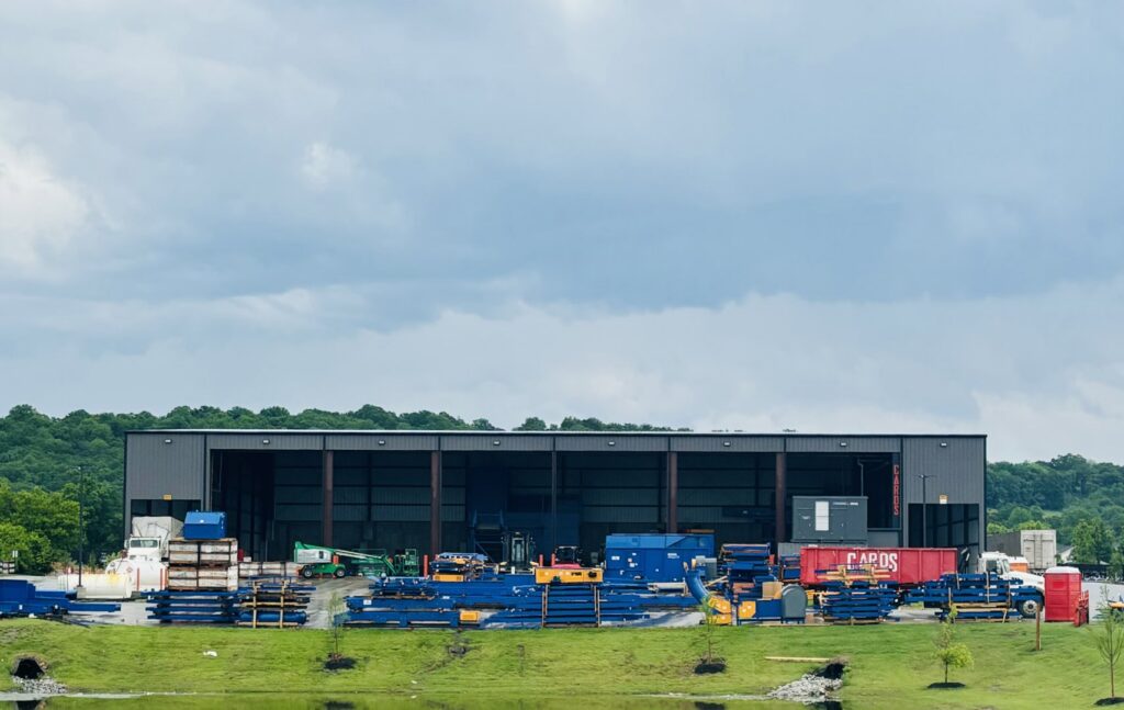 Exterior view of the CARDS waste management facility with equipment and a pond in Springdale, AR
