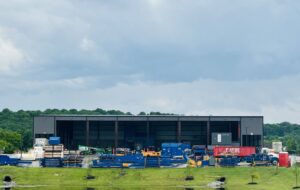 Exterior view of the CARDS waste management facility with equipment and a pond in Springdale, AR