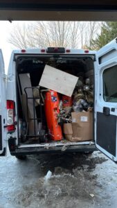 A Rubbish Doctor cargo van with open doors, loaded with various junk items for removal in Portland, ME.
