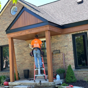 A skilled carpenter installing wood trim on a front porch at a home by New Life Custom Carpentry in Livonia, MI.
