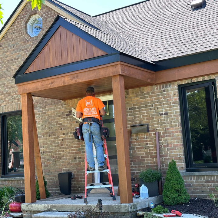A skilled carpenter installing wood trim on a front porch at a home by New Life Custom Carpentry in Livonia, MI.