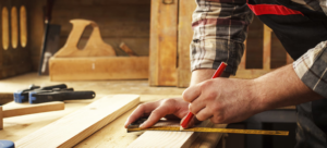 A carpenter's hands marking a piece of wood with a ruler and pencil for a project by Lincoln Handyman Services in Lincoln, NE
