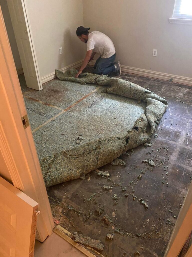 A worker removing old carpet padding, preparing the floor for new installation by SMM Services LLC in Gulfport, MS.