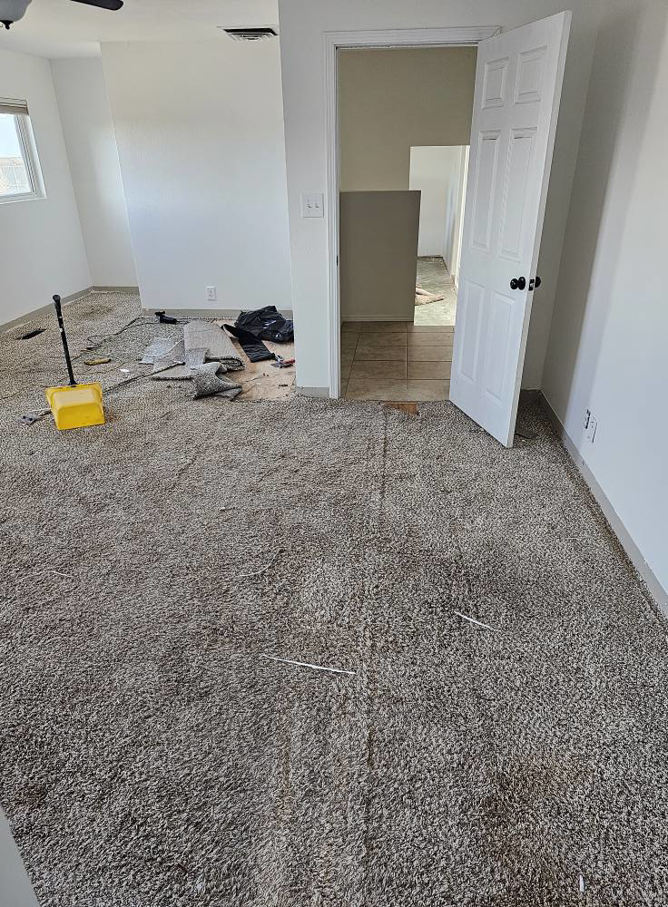 Carpet removal and floor preparation in a room, showing debris and subfloor by AV Handyman Services in Rio Rancho, NM.
