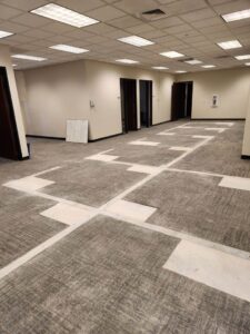 Office space with carpet tiles removed, showing debris from floor demolition and junk removal by HAVOC Demolition in Scottsdale, AZ.